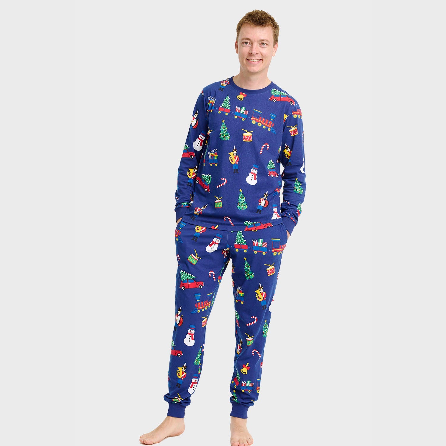 Weihnachtspyjama Herren aus blauem Baumwollstoff mit bunten Weihnachtsmotiven wie Schneemännern und Tannenbäumen.