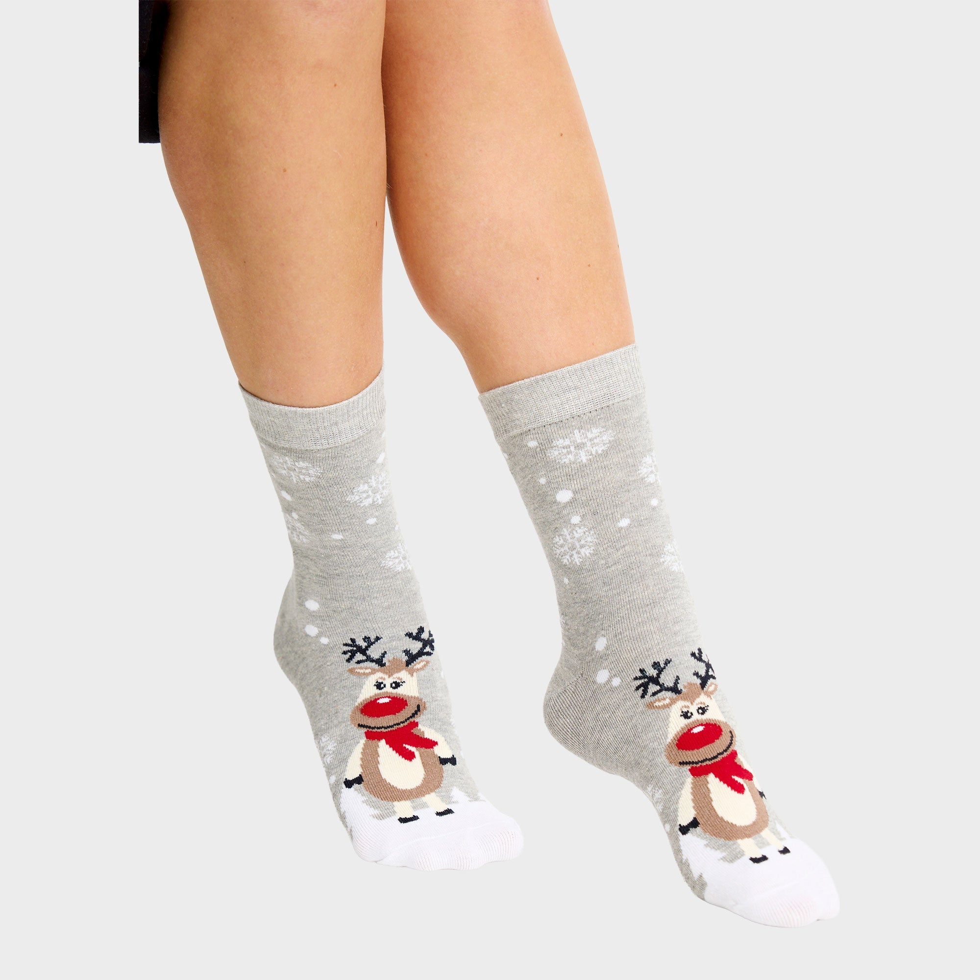 Ein Paar Beine mit grauen Weihnachtssocken mit Rudolph drauf.