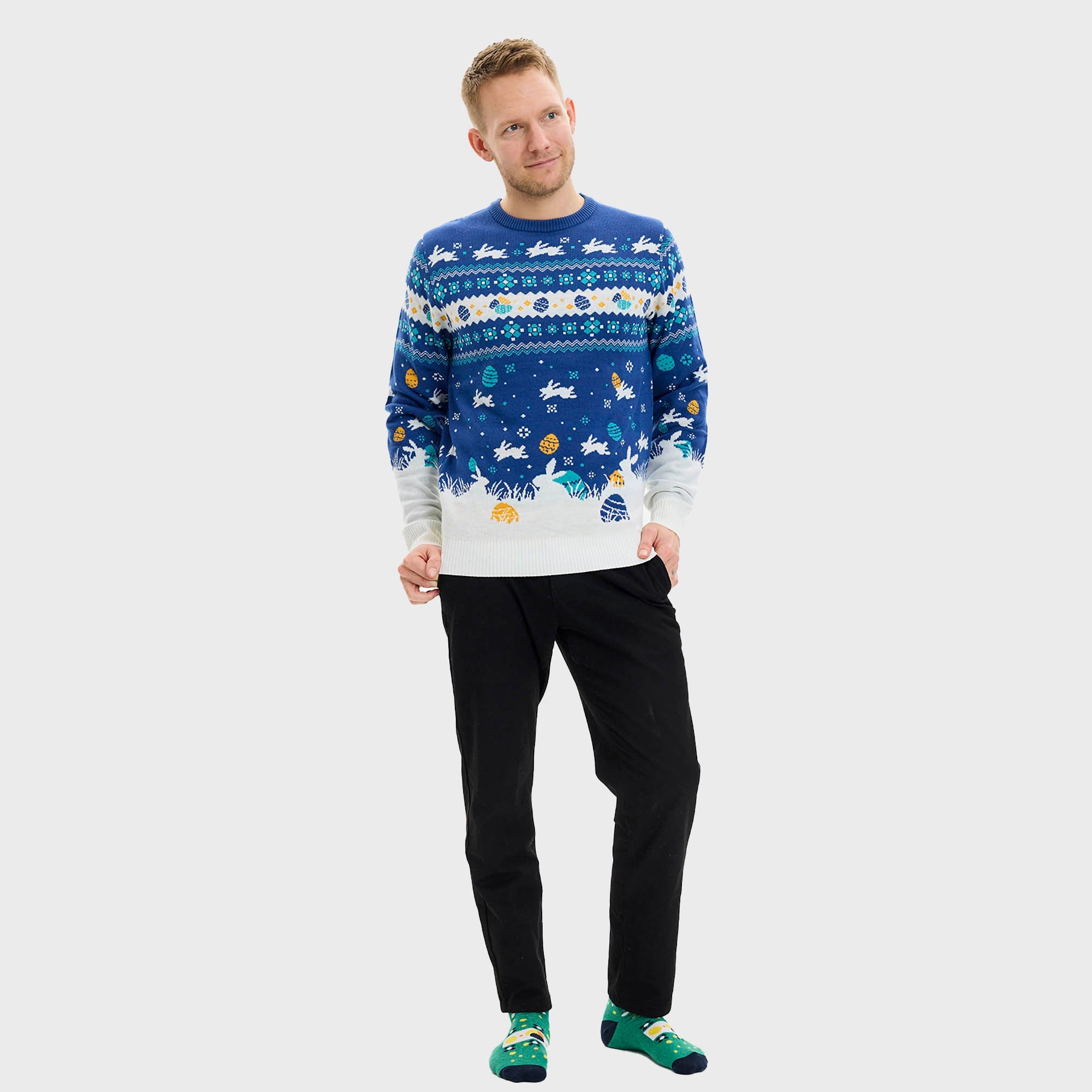 Ein Paar, das einen laufenden Hasen beobachtet, trägt einen blauen Osterpulli mit Ostereiern