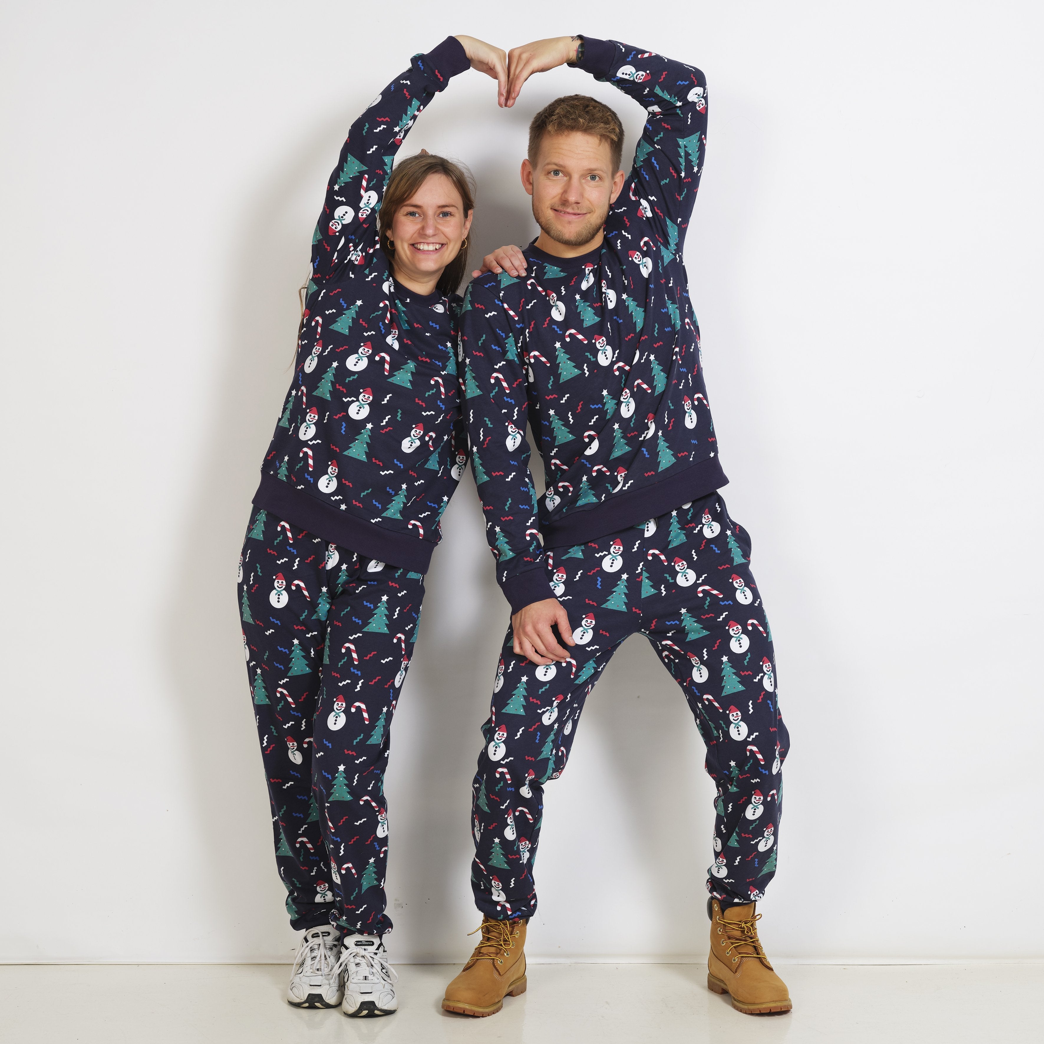 Eine Frau in einem dunkelblauen Weihnachtspulli mit Weihnachtsbäumen und Schneemännern.