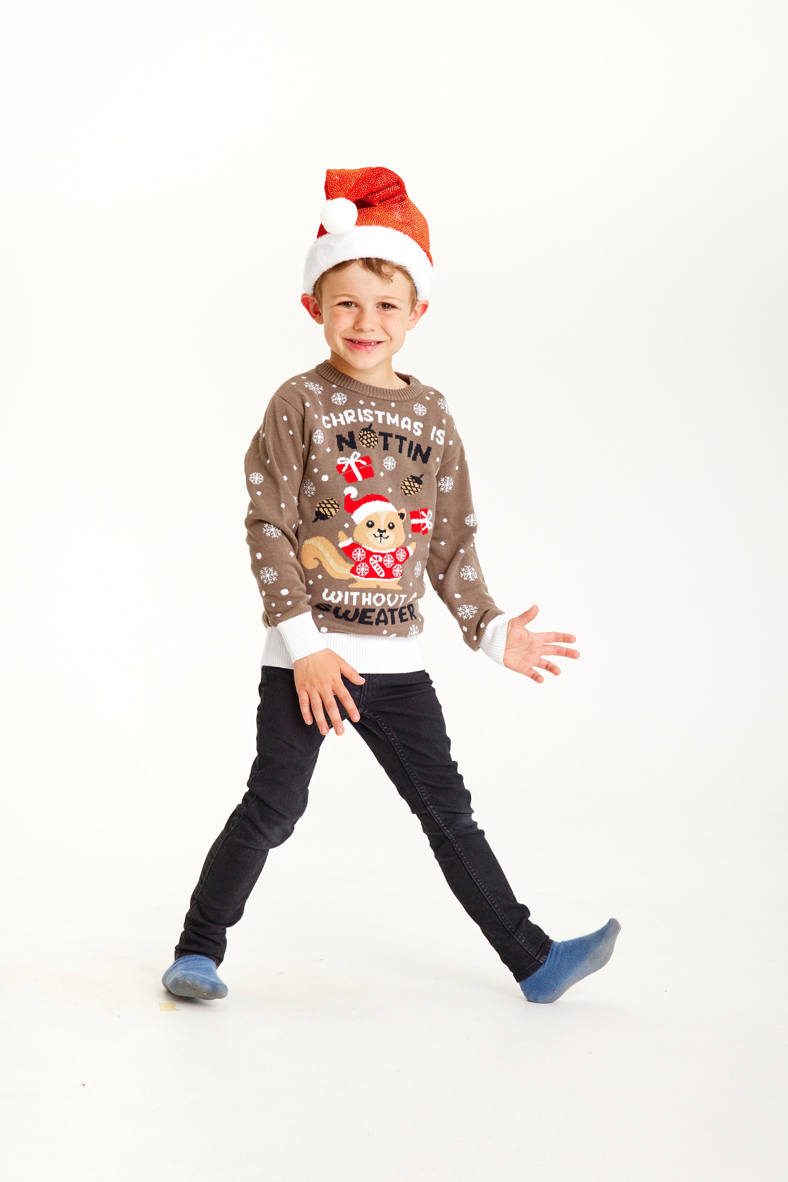 Ein Kind posiert mit einem braunen Weihnachtspulli mit einem Eichhörnchen darauf.