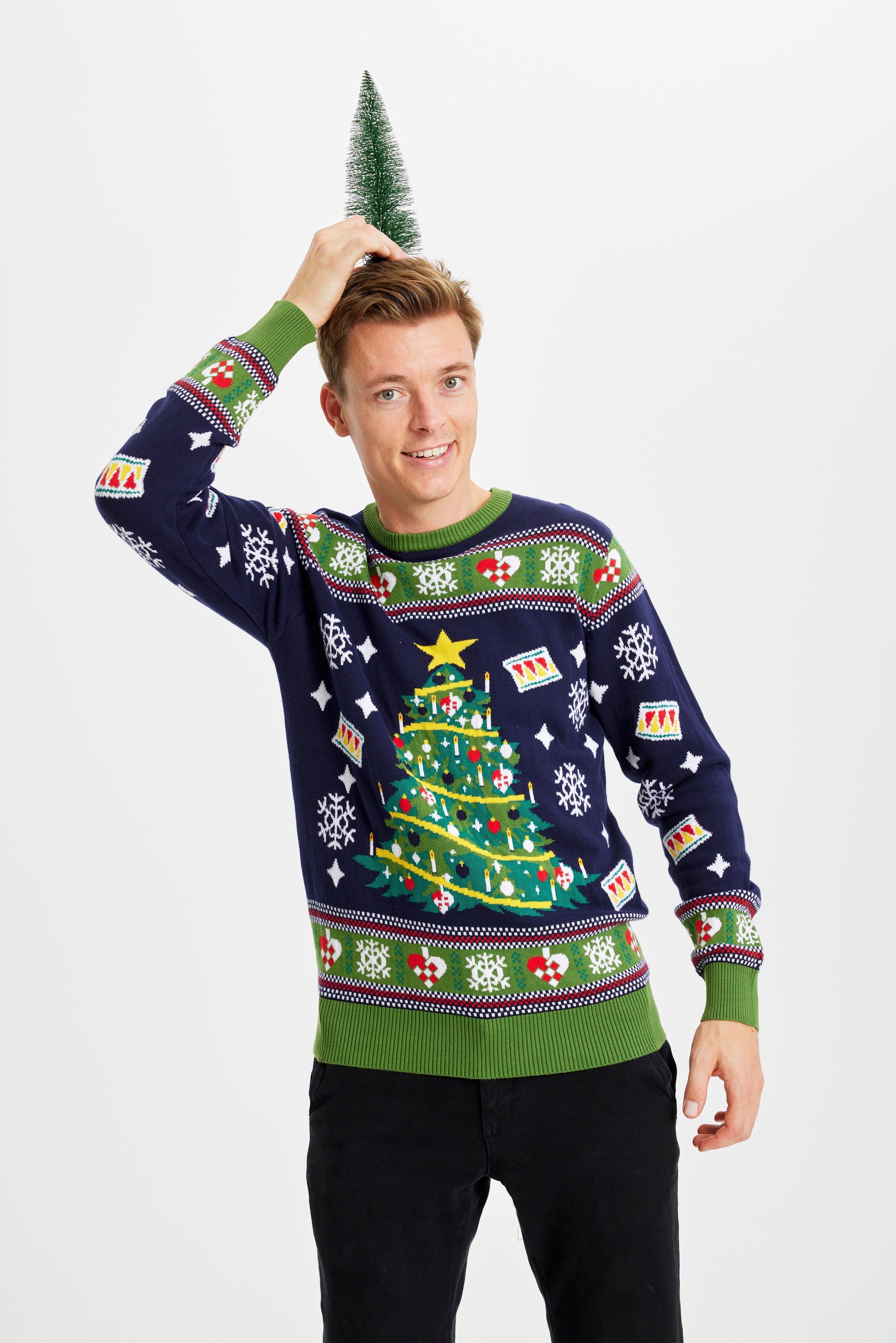 Ein Mann mit einem Weihnachtsbaum auf dem Kopf trägt einen blauen und grünen Weihnachtspulli mit einem Weihnachtsbaum.