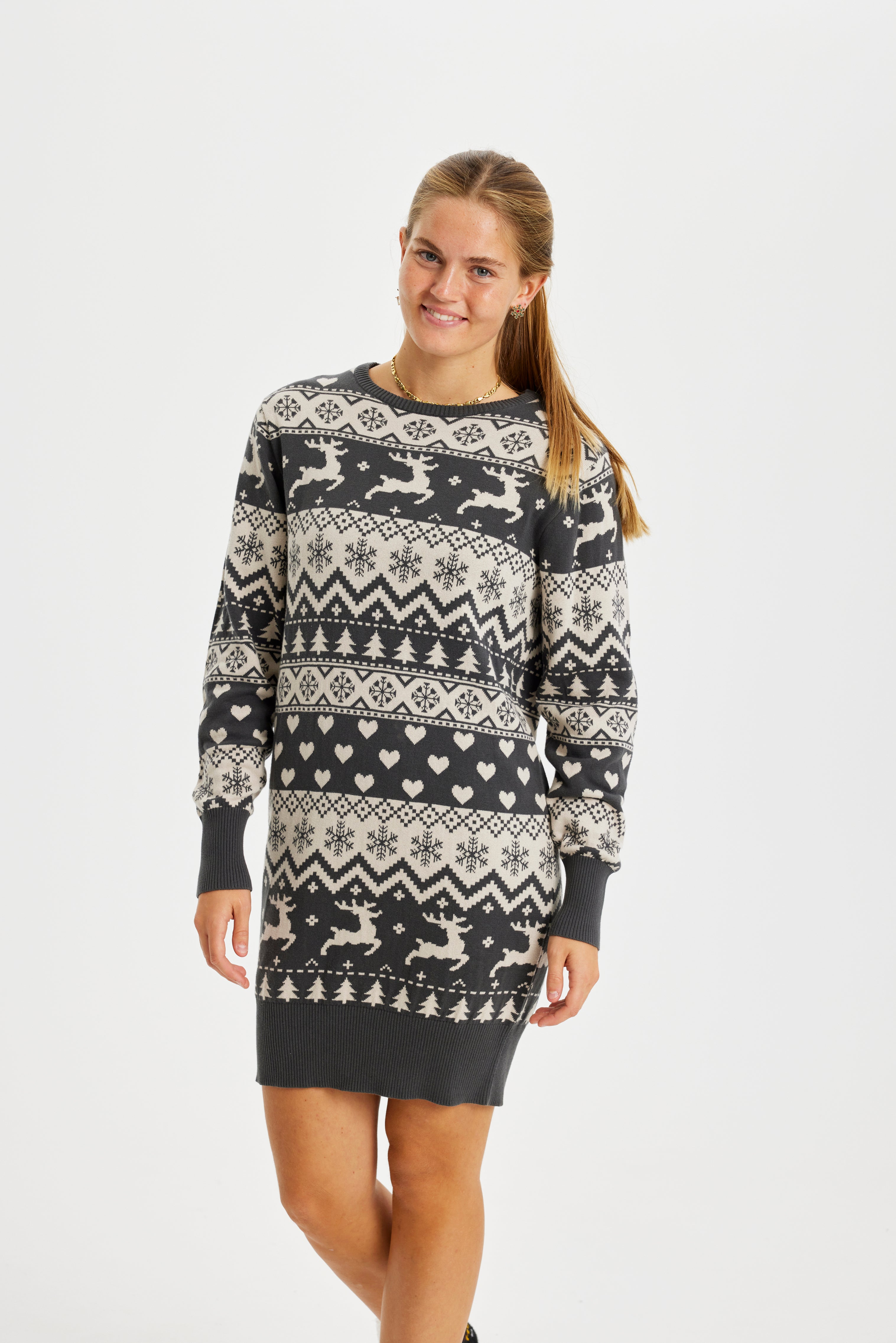 Eine lächelnde Frau in einem grauen Weihnachtskleid mit Rentieren.