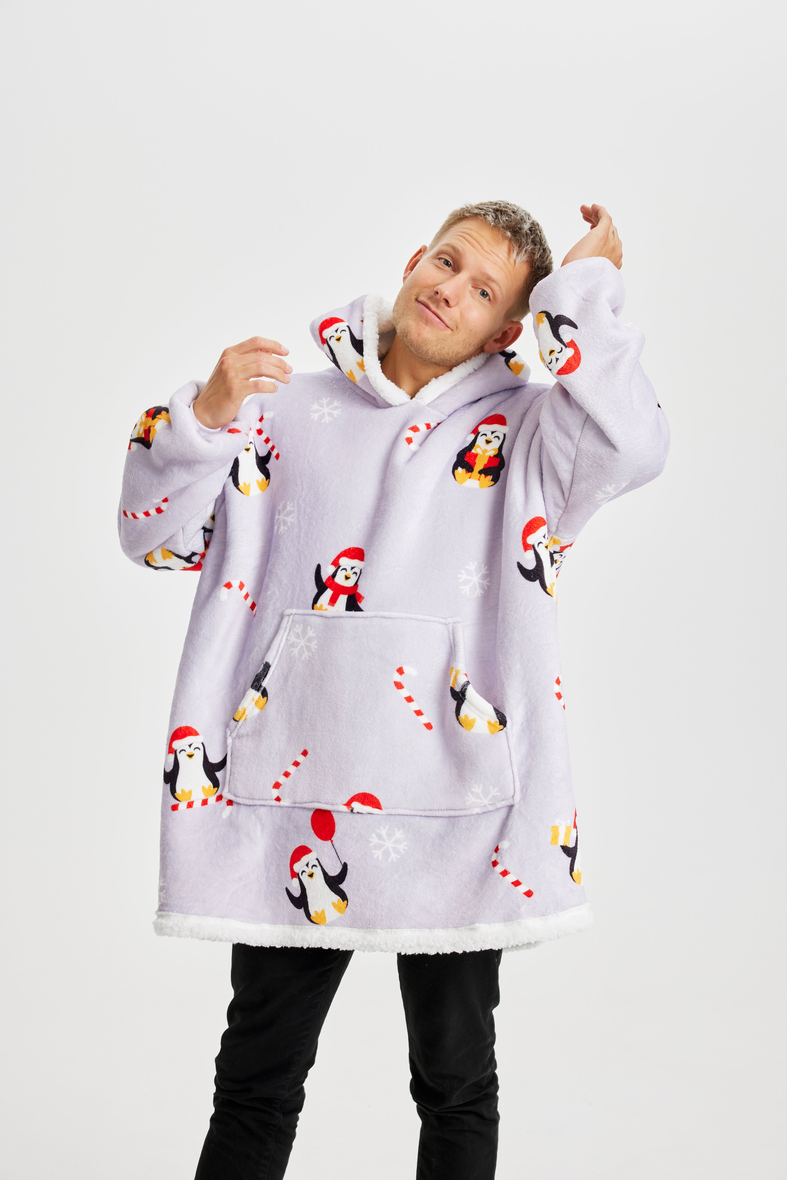 Ein posierender Mann, der einen hellvioletten Weihnachts-Kapuzenpullover mit Pinguinen darauf trägt.