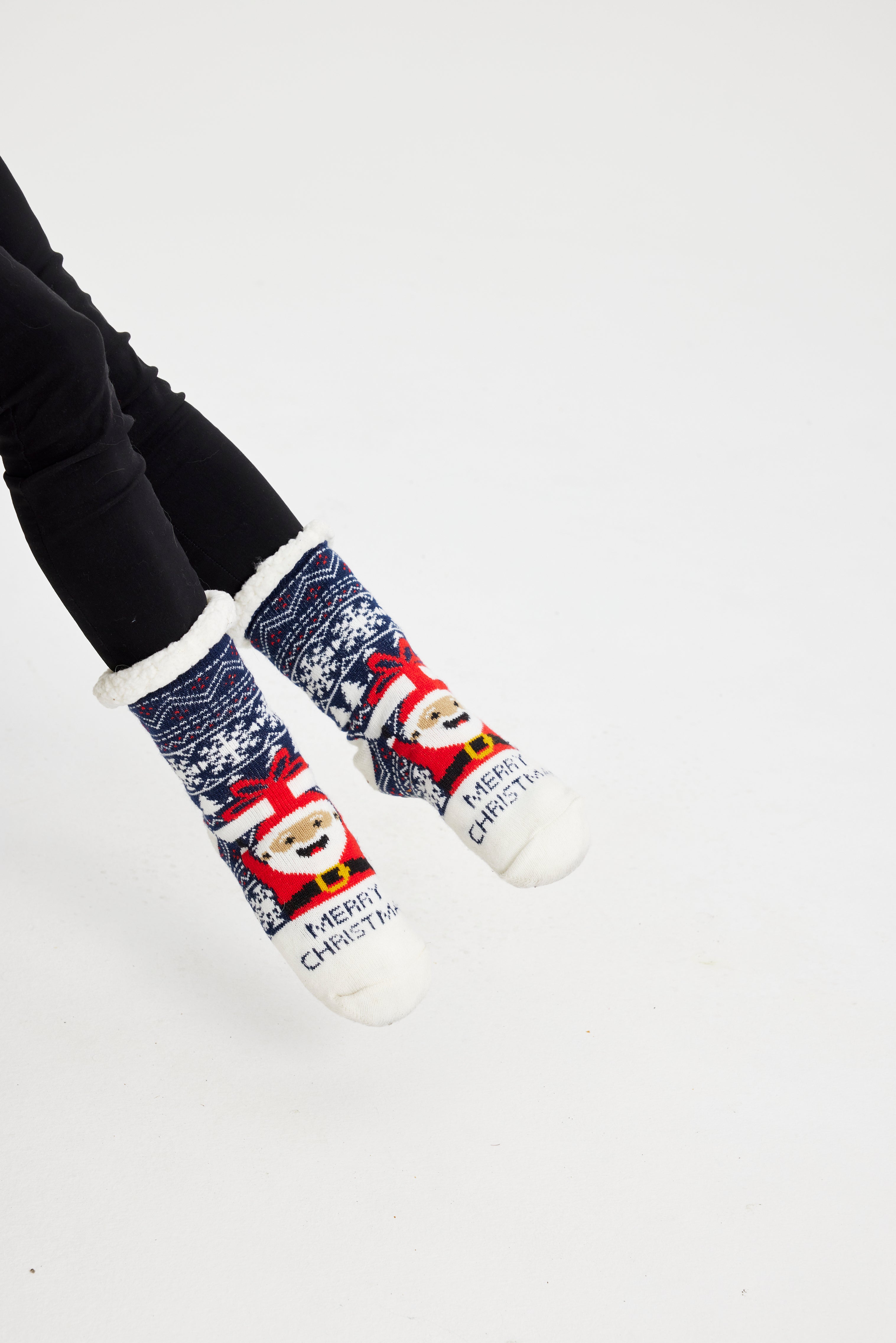 Ein Paar Beine, die ein Paar Weihnachtssocken mit dem Weihnachtsmann darauf tragen.