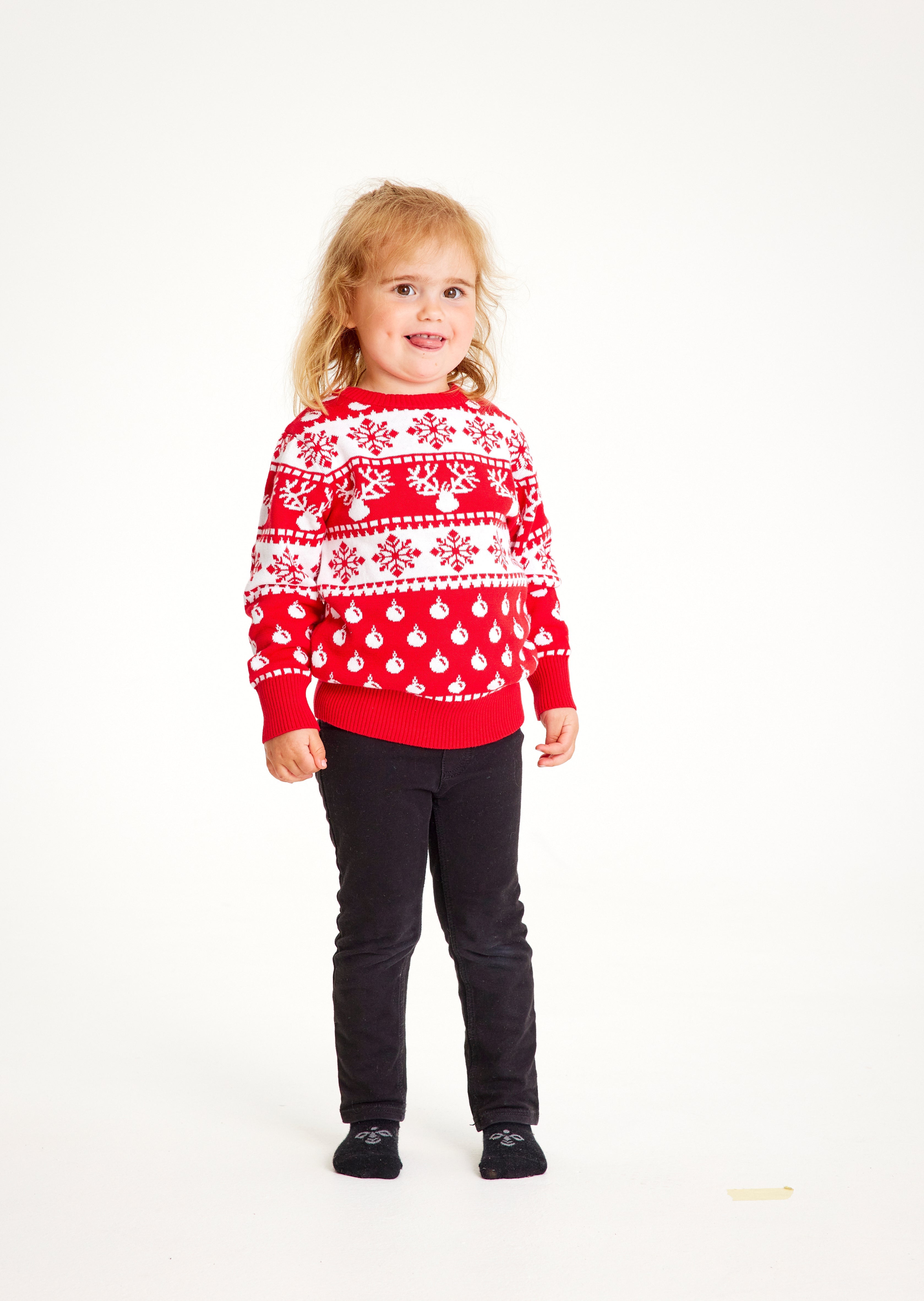 Ein Kind trägt einen rot-weißen Weihnachtspulli mit Schneeflocken.