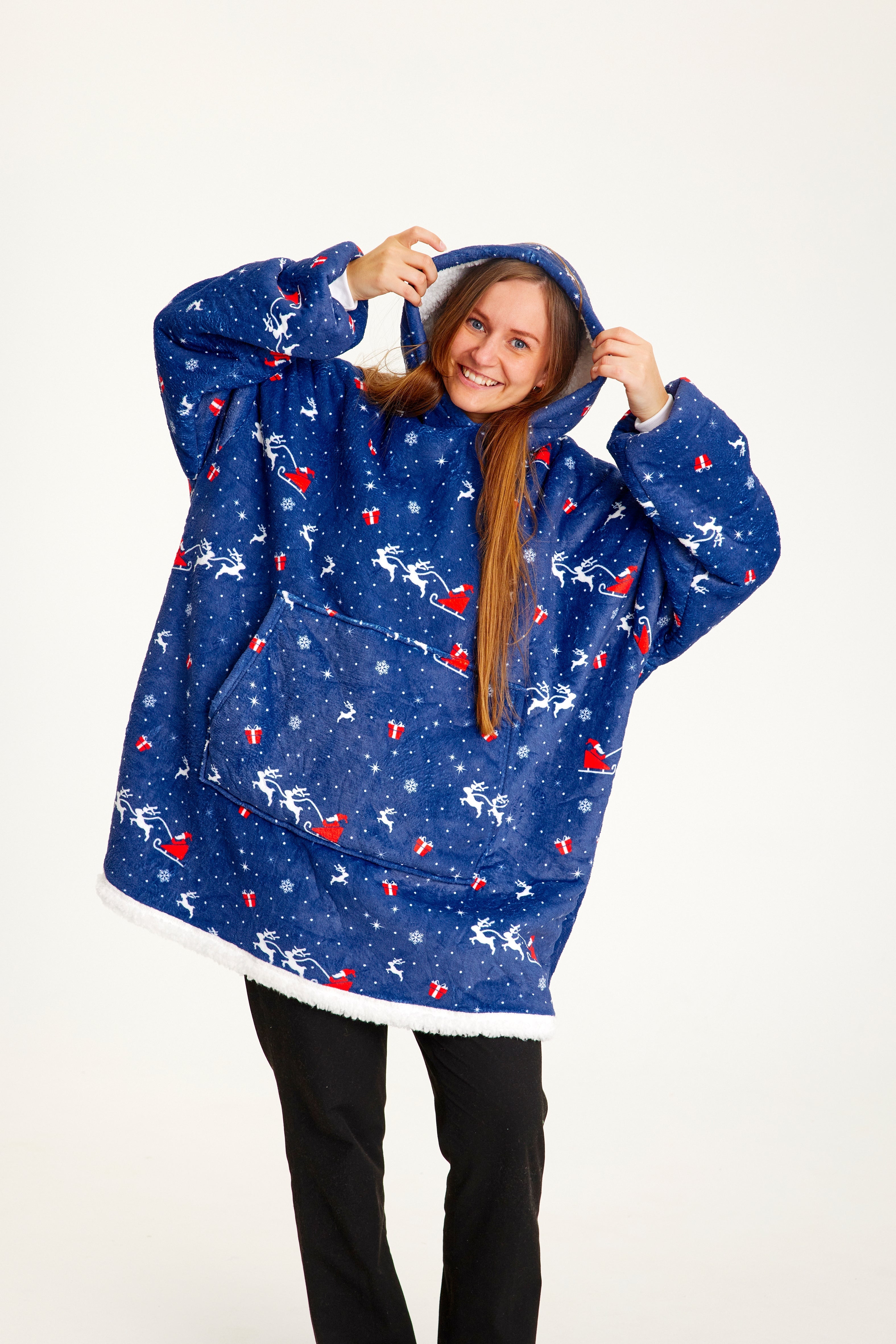 Eine lächelnde Frau, die einen blau gemusterten Weihnachts-Kapuzenpullover trägt.