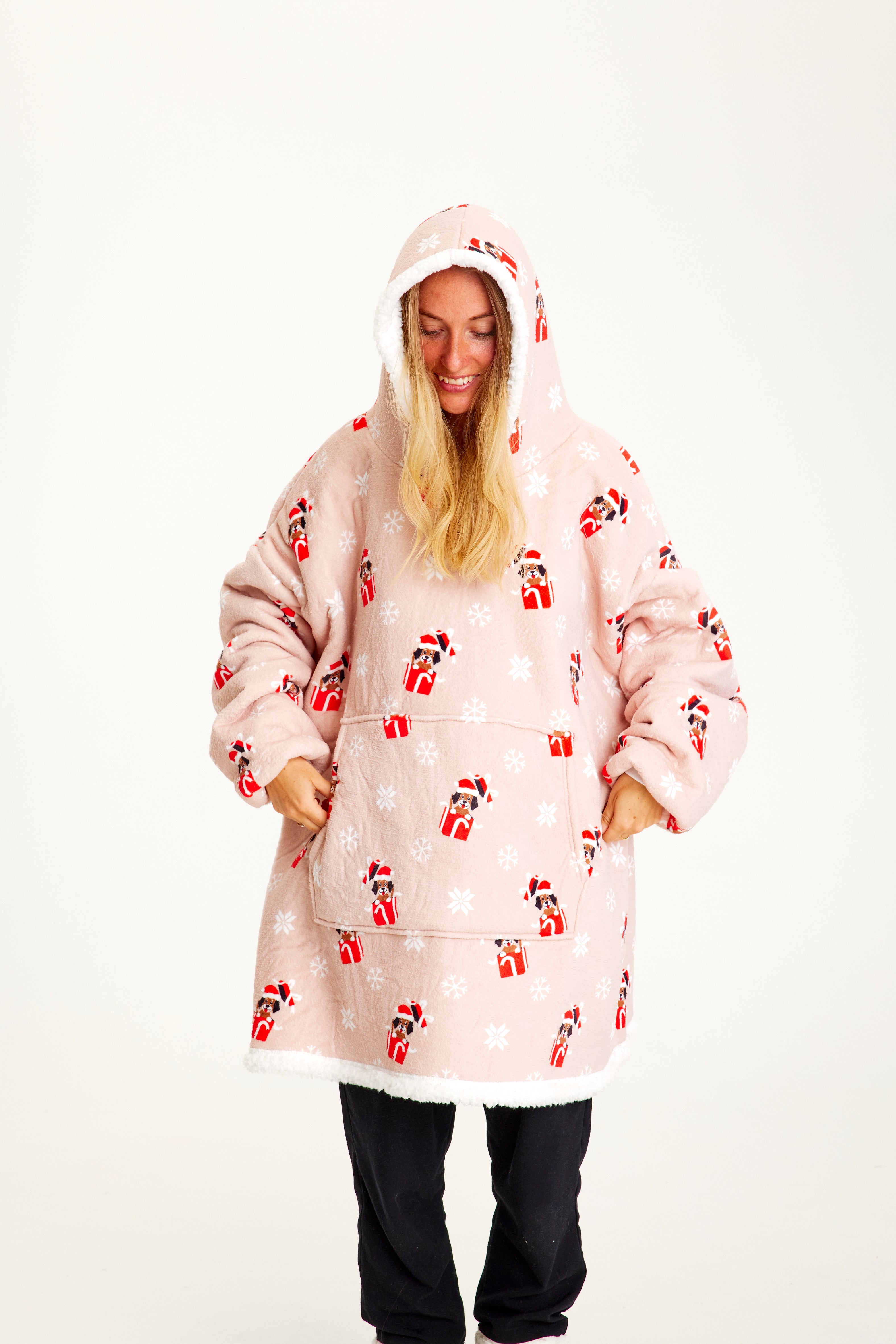 Eine Frau blickt nach unten und trägt einen rosafarbenen Weihnachtskapuzenpullover mit Hunden darauf.